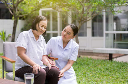 Nurse holding legs elderly Asian woman with knee pain,Take care and support conceptの写真素材