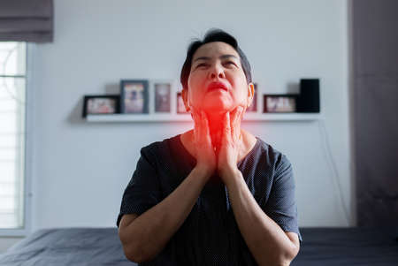 Elderly Asian woman have a sore throat, Female touching her neck with hand, Seasonal infections,...