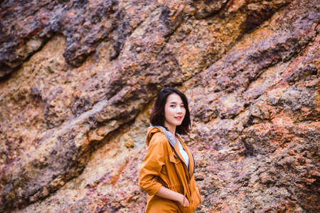 Portrait of traveler asian woman standing near cliff and looking camera at outdoor,Happy and smilingの写真素材