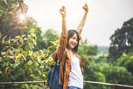 Portrait of traveler asian woman standing and hands raise up at outdoor with flare light,Happy and smilingの写真素材