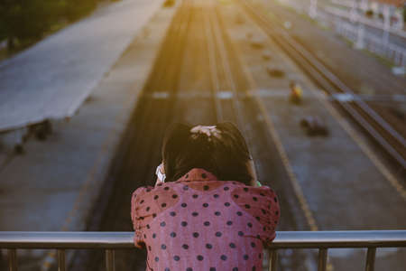 Depressed young asian woman standing on a bridge near railway at train station. Nagative attitudeの写真素材