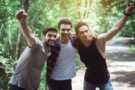 Happy man traveler friends hugging with hands raise up together at nature,Enjoying backpacking conceptの写真素材