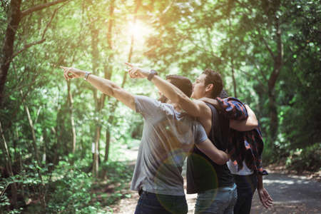 Happy traveler friends hugging and pointing something together at nature,Enjoying backpacking conceptの写真素材