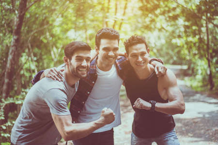Cheerful young  man traveler friends hugging with hands raise up together at nature,Enjoying backpacking conceptの写真素材