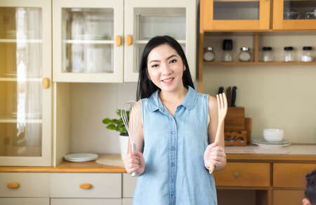 Beautiful young asian woman cooking in the kitchen,Happy and smilingの写真素材