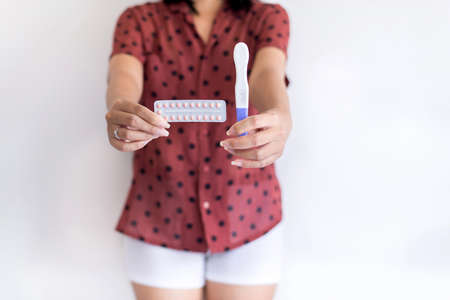 Woman hands holding birth control pill and pregnancy test,Concept for contraceptive,Copy space for text on white backgroundの写真素材