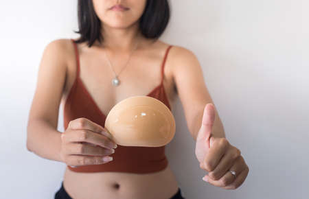 Woman hands holding silicone implants for breast and showing thumb up,Copy space for text on white backgroundの写真素材
