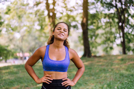 Portrait of black beautiful woman standing and resting after break workout at park,Happy and smiling,Relaxing timeの写真素材