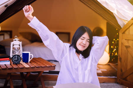 Beautiful asian woman stretching in tent after wake up in the morning,Happy and smiling,Relaxing...