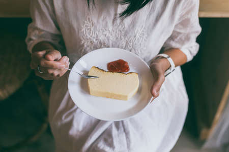 Woman hands holding and eating butter cake with strawberry jam at a cafe,Close upの写真素材
