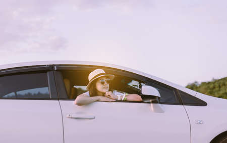 Hipster asian woman wearing hat and sunglasses sitting in her car at outdoor,Relaxing time,Positive thinkingの写真素材