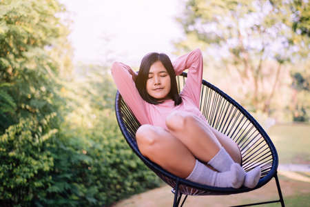 Beautiful young asian woman sitting with hands on her head and sleeping on modern chair at nuture,Relaxing time,Happy and smilingの写真素材