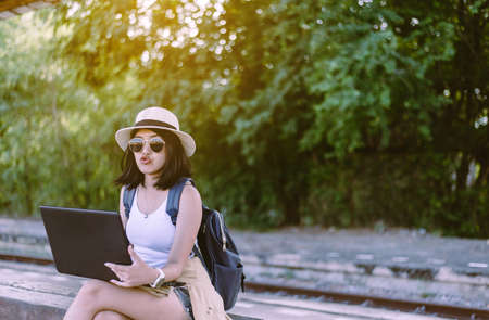 Hipster asian woman tourist using internet with laptop computer and waiting train at train station,Travel and vacation conceptの写真素材