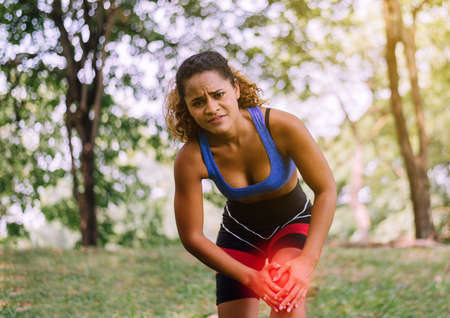 Sporty black woman suffering on her knee,Athlete female having pain on kneeの写真素材