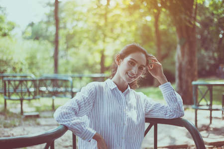 Beautiful confidence woman sitting and looking something at outdoor in the morning,Happy and smiling,Relaxing time,Positive thinkingの写真素材