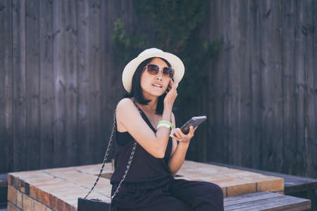 Beautiful asian woman using mobile phone while sitting at outdoor,Happy and smiling,Relaxing...