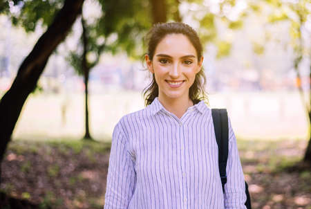 Happy young student woman standing and looking to camera at public park in the morning,Happy and...