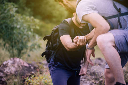 Close up of hand man getting help to bestfriends climb a rock,Helping hands,Overcoming obstacle conceptの写真素材