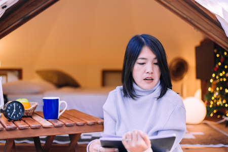 Asian woman drinking coffee and reading book, Happy and smiling, Positive thinking,Relax timeの写真素材