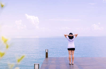 Happy woman standing with hands on head on wood bridge at sea,Enjoying in Nature,Freedom concept,Back viewの写真素材
