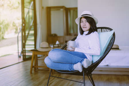 Beautiful asian woman drinking hot coffee in bedroom after wake up,Relaxing morning,Happy and smiling,Healthy and lifestyle conceptの写真素材