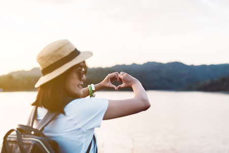 Hipster young asian woman showing hands heart shape at nature sunset,Travel insurance conceptの写真素材