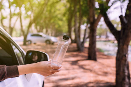 Woman hand holding plastic bottle on the road,Global warming environmental protection concept