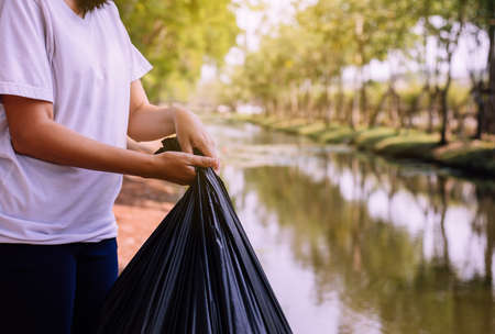 Woman hand holding black color garbage bag,Dispose waste management and plastic recycle concept,Close upの写真素材