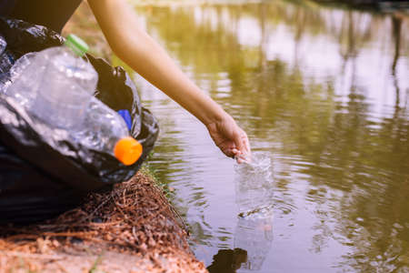 Woman volunteer picking up a bottle plastic trash in river,Environment conceptの写真素材