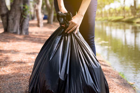 Woman volunteer holding black color garbage bag at park,Dispose plastic recycle and waste management concept,Close upの写真素材
