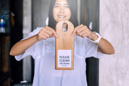 Woman hands holding please clean the room sign of hotel roomの写真素材
