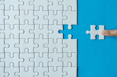 Woman hands putting Jigsaw puzzles,Jigsaw white color,Puzzles pieces grid,Success mosaic solution...