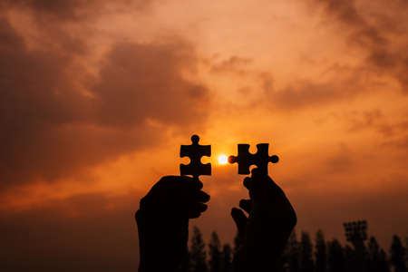 Business success and strategy solutions concept,Hands woman connect couple puzzle piece together with sunlight backgroundの写真素材