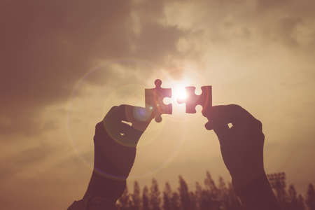 Business success and strategy solutions concept,Hands woman connect couple puzzle piece together with sunlight backgroundの写真素材