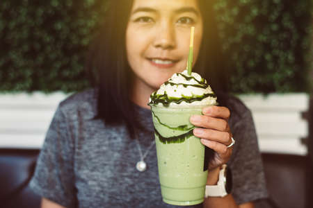Happy asian woman drinking iced green tea at modern cafe,Relax time