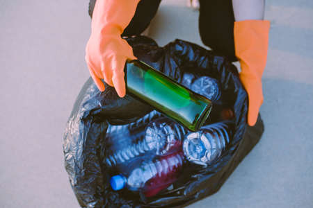 Volunteer women hand holding black color garbage bag with keeping glass bottle at beach,Dispose...