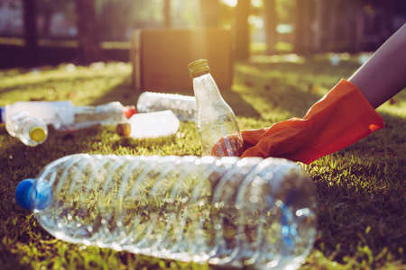 Volunteer woman hands holding and keep trash on green grass,Good conscious mind,Dispose recycle and waste management conceptの写真素材