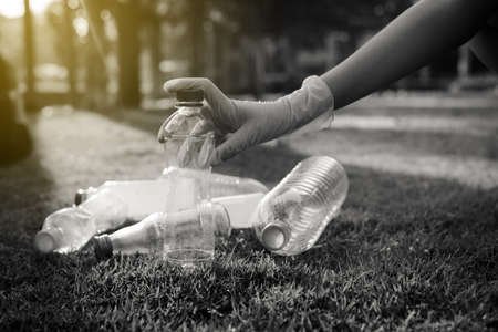 Volunteer woman hands keep plastic bottle on green grass,Good conscious mind,Dispose recycle and waste management concept,Black and white tonedの写真素材