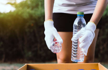 Volunteer women keep plastic bottle into paper box at public park,Dispose recycle and waste management concept,Good conscious mindの写真素材
