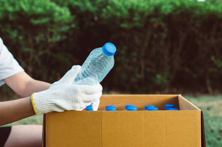 Volunteer woman keep plastic bottle into paper box at public park,Dispose recycle and waste management concept,Good conscious mindの写真素材