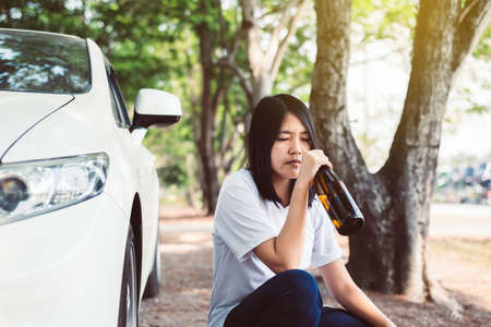 Drunk asian woman drinking alcohol while driving car on road,Women drive her car with a bottle of...