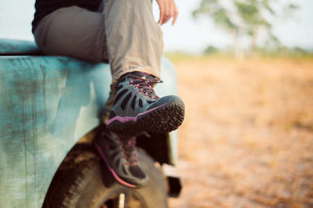 Traveller female sitting on car at nature,Hiking shoes woman in beautiful view,Road trip