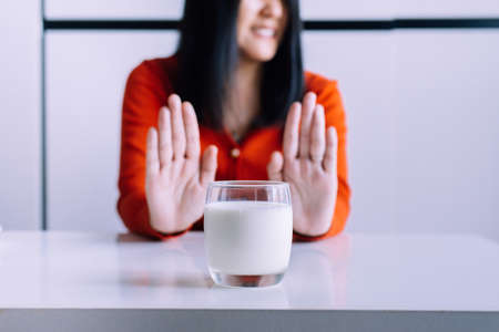 Woman hands refusing a glass of milk,Female having allergy milk,Lactose intolerance conceptの写真素材