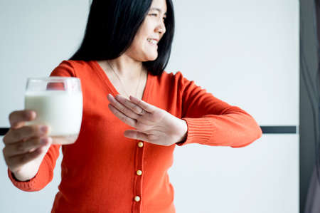 Woman hands refusing a glass of milk,Female having allergy milk,Lactose intolerance conceptの写真素材