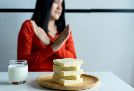 Woman hands refusing white bread,Female having allergy to bread,Food intolerance defined conceptの写真素材