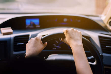 Hands woman holding steering wheel,Driving a car on roadの写真素材