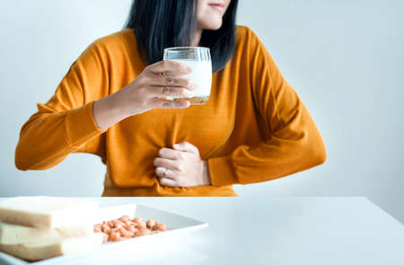 Woman having a stomach pain with a glass of milk at home,Allergy dairy intolerant,Lactose intolerance conceptの写真素材