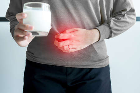 Allergy dairy intolerant,Lactose intolerance concept,Asian woman having a stomach pain with a glass of milkの写真素材