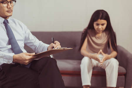 Professional psychologist talking with asian woman patient and writing notes,Therapist conducting a consultation and counseling to womenの写真素材