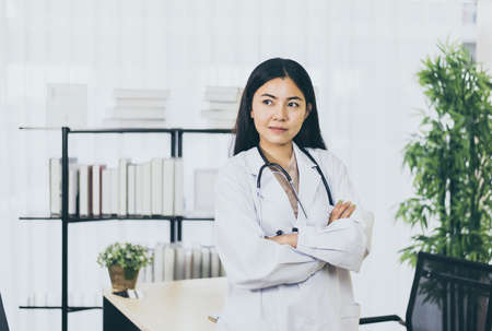 Portrait of young asian doctor woman in white coat standing in hospitalの写真素材